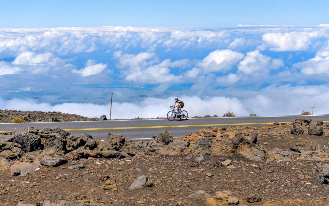 A female bicyclist riding above the clouds on Haleakala Highway.